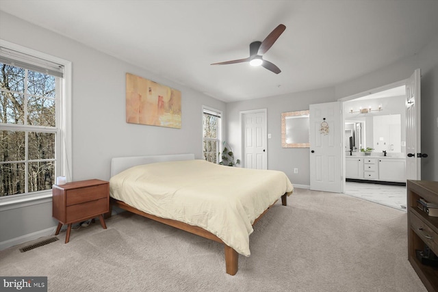 bedroom with light colored carpet, visible vents, a ceiling fan, connected bathroom, and baseboards