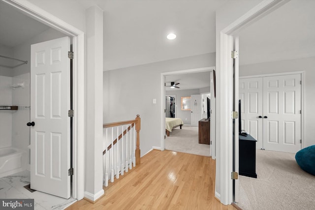 corridor featuring marble finish floor, recessed lighting, baseboards, and an upstairs landing