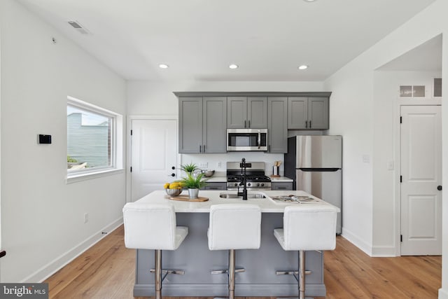 kitchen featuring appliances with stainless steel finishes, light wood-type flooring, visible vents, and gray cabinetry