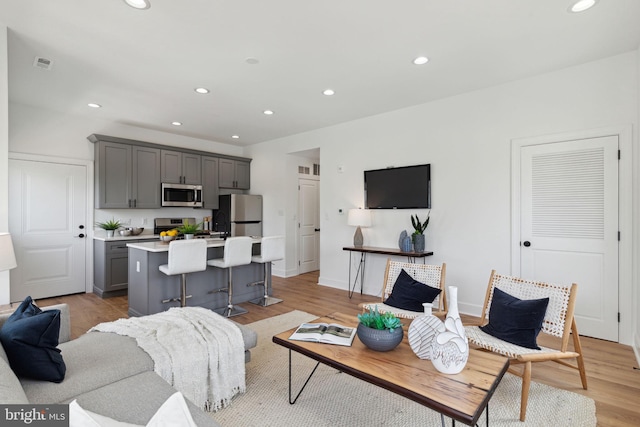 living area featuring light wood-style flooring, visible vents, baseboards, and recessed lighting