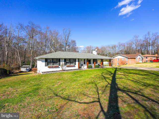 ranch-style home featuring covered porch, a chimney, and a front yard