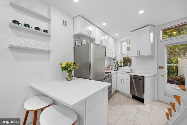 kitchen with visible vents, light countertops, appliances with stainless steel finishes, a peninsula, and white cabinets