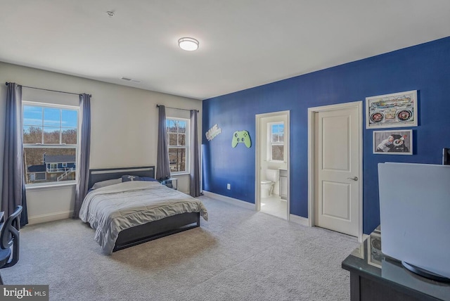 bedroom with light carpet, ensuite bathroom, baseboards, and multiple windows