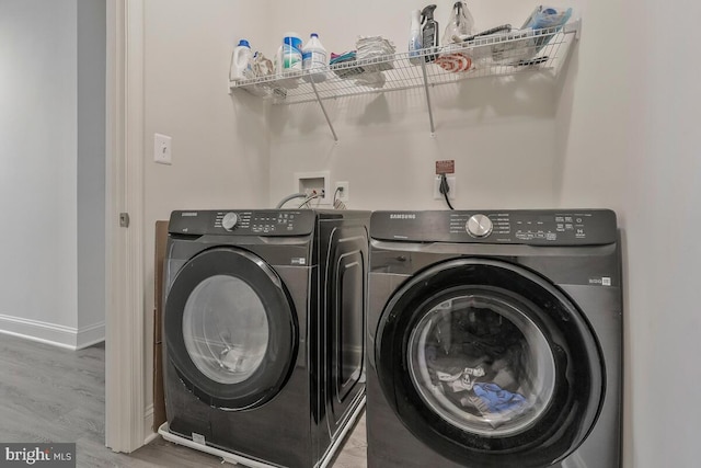 laundry room with washer and dryer, laundry area, baseboards, and wood finished floors