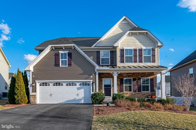 craftsman house featuring driveway, stone siding, an attached garage, and covered porch