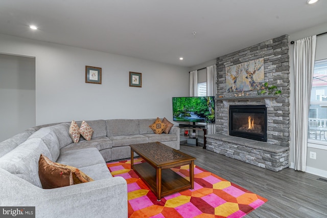 living room featuring recessed lighting, visible vents, wood finished floors, and a stone fireplace