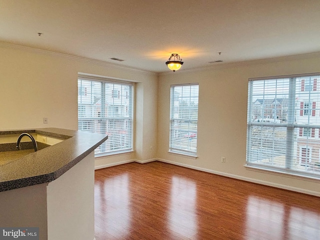 unfurnished dining area with baseboards, wood finished floors, visible vents, and crown molding