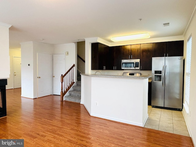 kitchen with stainless steel appliances, light countertops, light wood-style floors, and visible vents