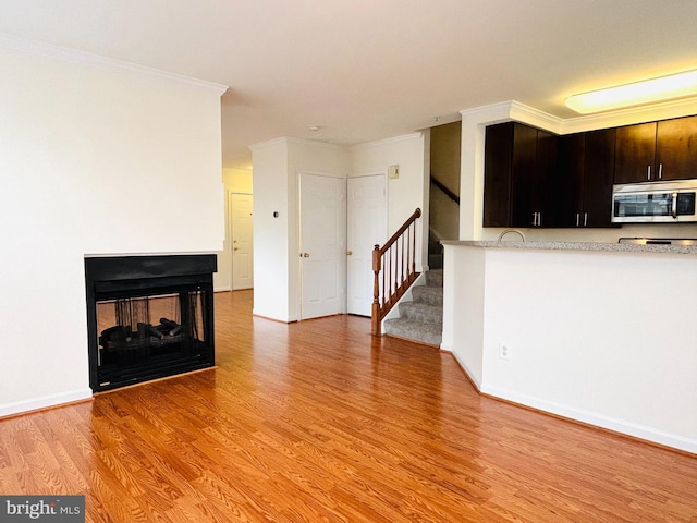 unfurnished living room with baseboards, ornamental molding, stairs, light wood-type flooring, and a multi sided fireplace