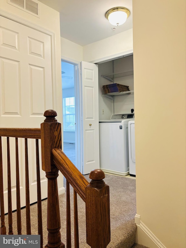 corridor with separate washer and dryer, visible vents, an upstairs landing, baseboards, and carpet