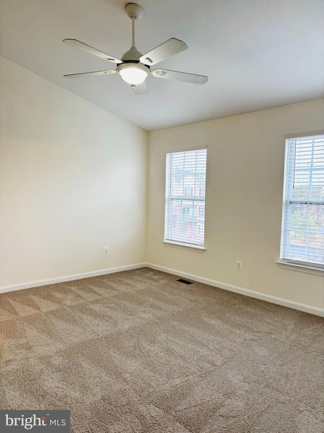 empty room with carpet, lofted ceiling, visible vents, ceiling fan, and baseboards