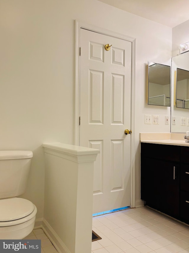 bathroom featuring baseboards, vanity, toilet, and tile patterned floors