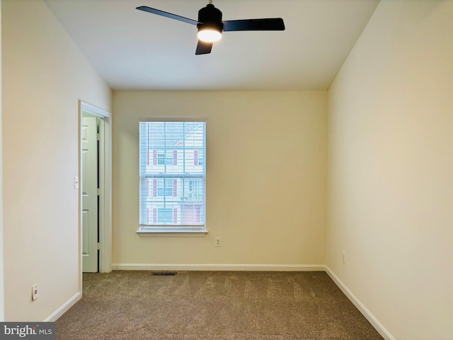 carpeted spare room featuring ceiling fan, visible vents, and baseboards