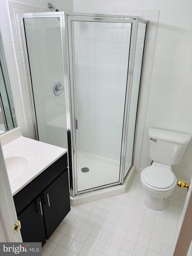 full bathroom featuring a stall shower, vanity, toilet, and tile patterned floors