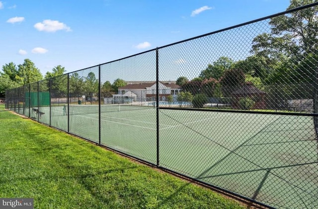 view of tennis court featuring a yard and fence