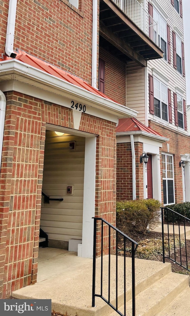 view of exterior entry featuring a garage and brick siding