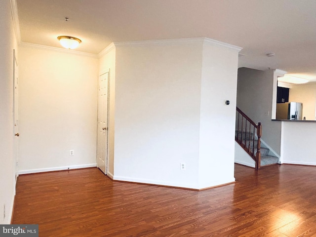 spare room with baseboards, crown molding, stairway, and wood finished floors