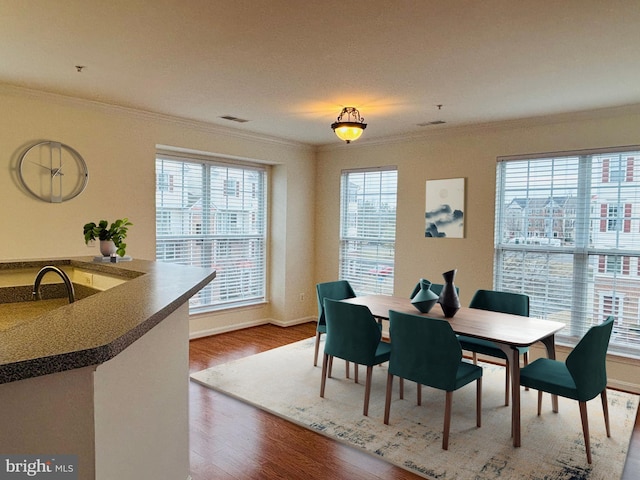 dining space with visible vents, crown molding, and wood finished floors