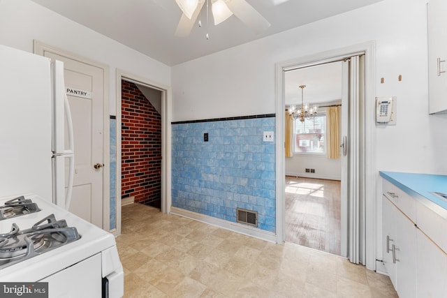 interior space with hanging light fixtures, white appliances, white cabinetry, and light countertops