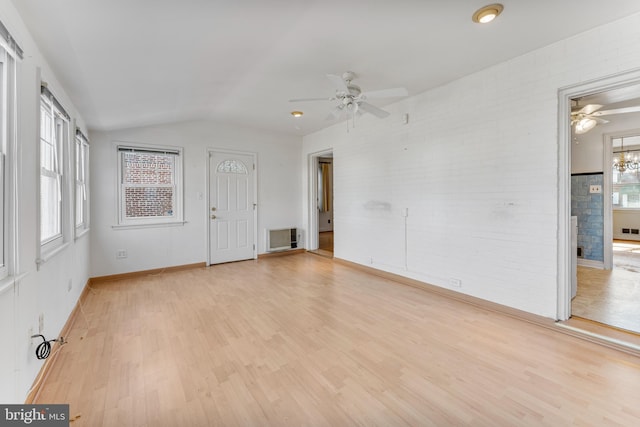 spare room with lofted ceiling, light wood finished floors, visible vents, and a wealth of natural light