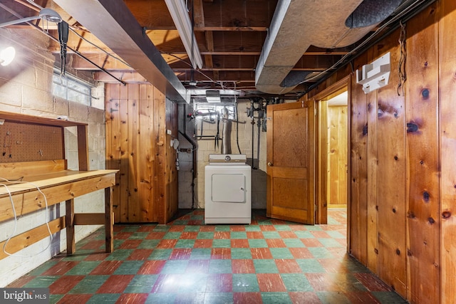 below grade area featuring wood walls, washer / dryer, and tile patterned floors