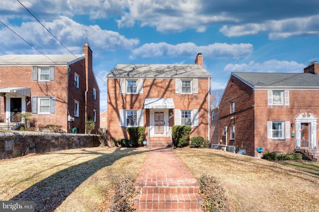 view of front of house with a front yard, a chimney, and brick siding