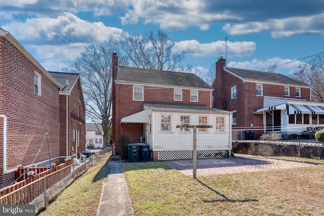 back of house with a yard, brick siding, a patio, and fence