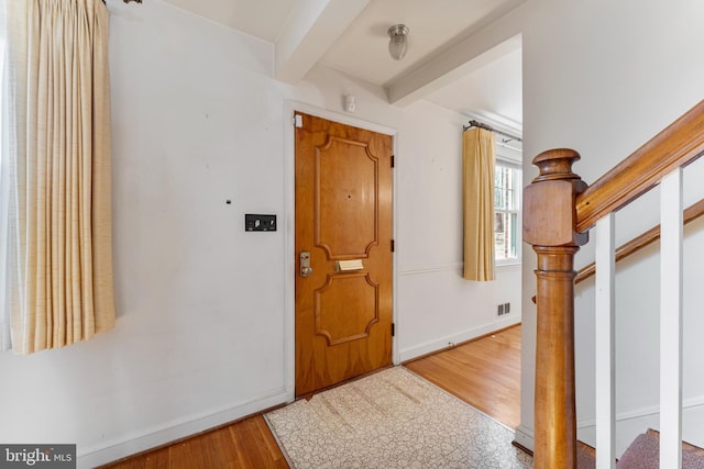 entrance foyer with baseboards, visible vents, stairway, wood finished floors, and beam ceiling