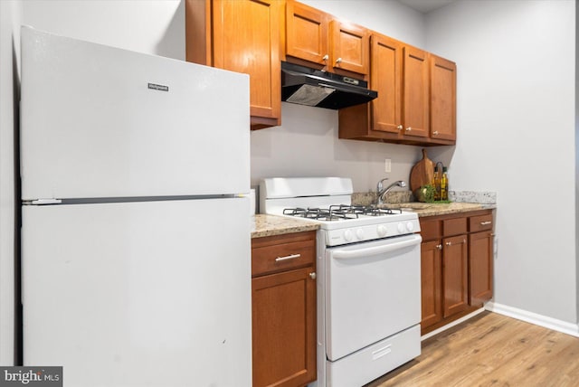 kitchen featuring white appliances, brown cabinets, a sink, and under cabinet range hood