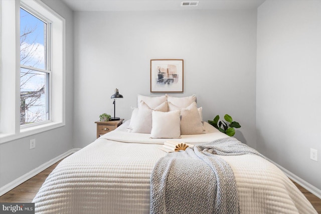 bedroom with multiple windows, baseboards, and wood finished floors