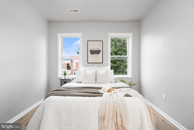 bedroom featuring visible vents, baseboards, and wood finished floors