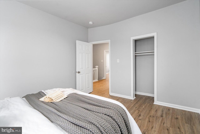 bedroom featuring a closet, wood finished floors, and baseboards