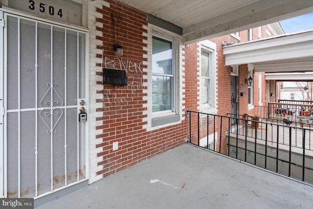 entrance to property featuring covered porch and brick siding