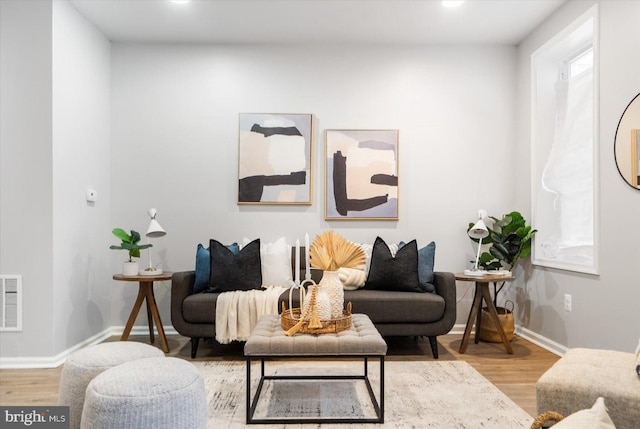 living room featuring baseboards, visible vents, wood finished floors, and recessed lighting