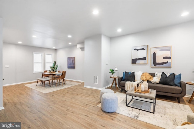 living area with recessed lighting, visible vents, baseboards, and wood finished floors