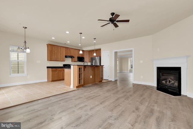 kitchen featuring under cabinet range hood, light wood-style floors, open floor plan, freestanding refrigerator, and dark countertops