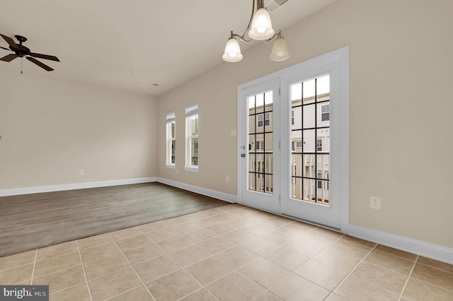 doorway to outside with ceiling fan with notable chandelier, baseboards, and tile patterned floors