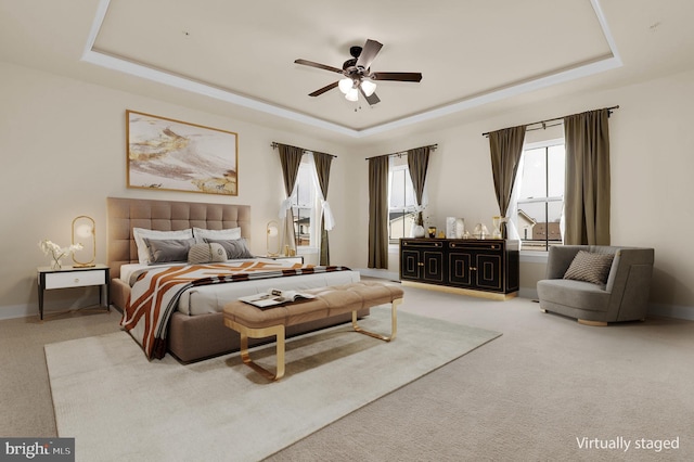 bedroom featuring light carpet, a tray ceiling, and baseboards