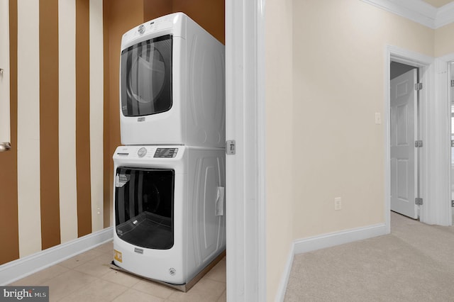 washroom with stacked washer / drying machine, laundry area, light carpet, and baseboards