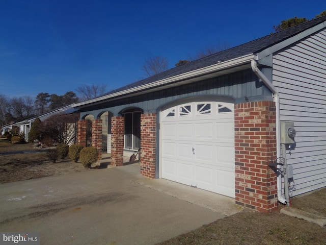 view of property exterior featuring a garage, concrete driveway, and brick siding