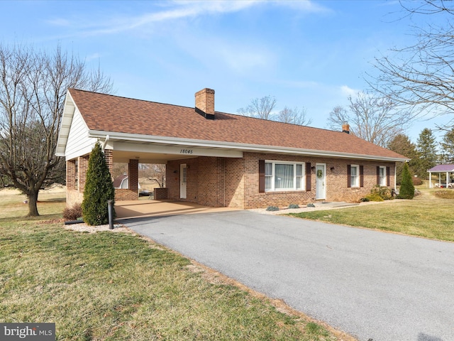 ranch-style house featuring brick siding, a shingled roof, aphalt driveway, a front yard, and a chimney