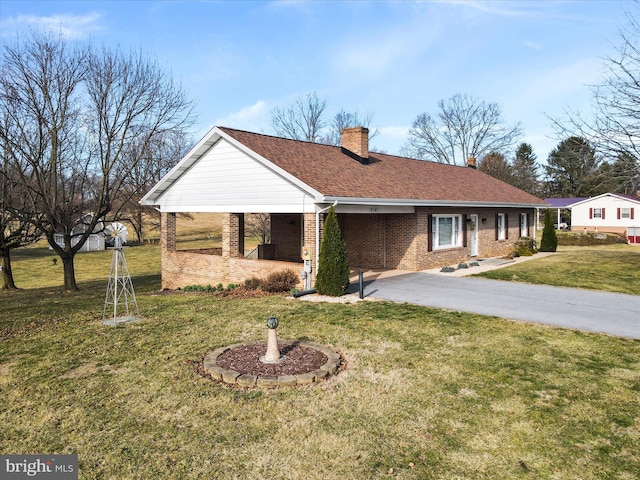 ranch-style house with aphalt driveway, roof with shingles, a front yard, brick siding, and a chimney