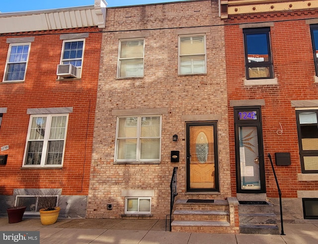 view of property with entry steps, brick siding, and cooling unit