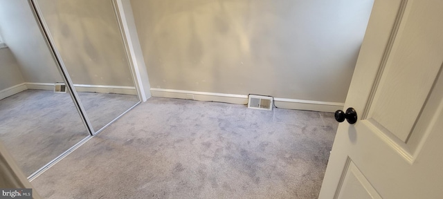 unfurnished bedroom featuring visible vents, multiple closets, and light colored carpet