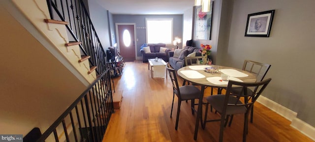 dining area featuring stairs, baseboards, and wood finished floors