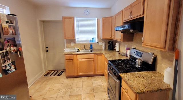 kitchen with decorative backsplash, gas stove, a sink, light stone countertops, and exhaust hood