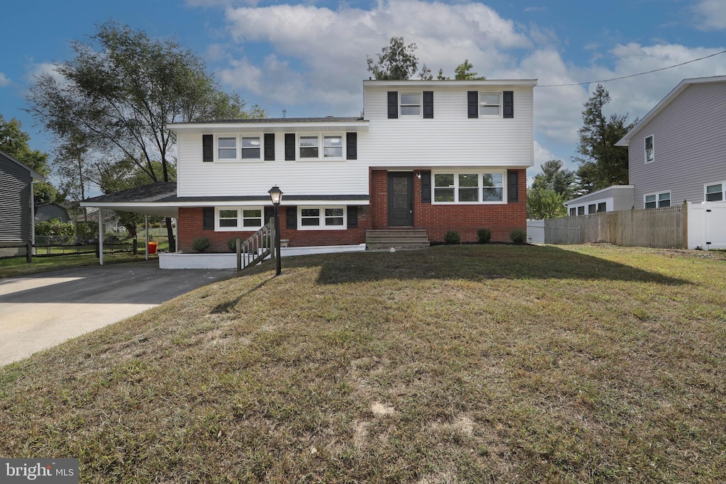 tri-level home featuring driveway, a front lawn, an attached carport, and brick siding