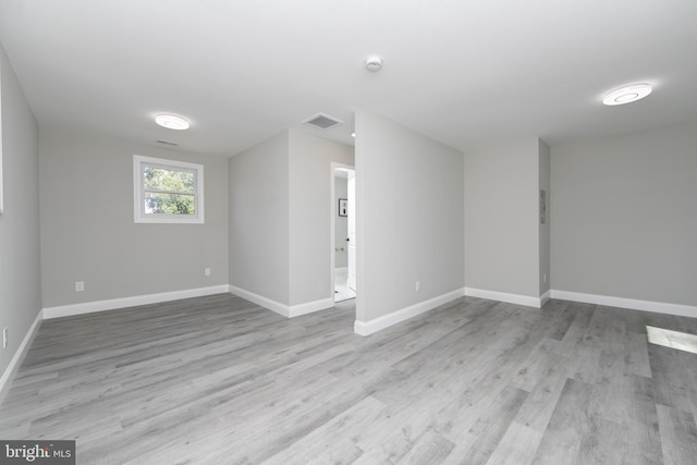 spare room featuring light wood-type flooring, visible vents, and baseboards