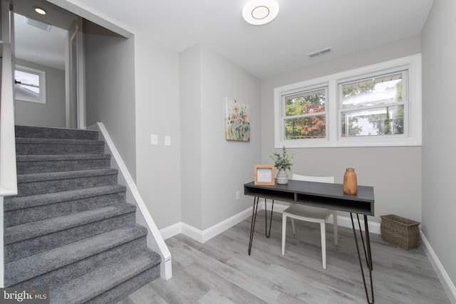 office area with light wood-style floors, visible vents, and baseboards