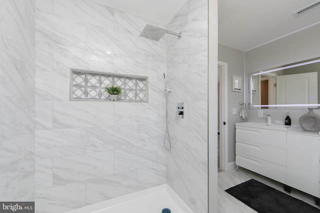 bathroom with marble finish floor, visible vents, vanity, and tiled shower